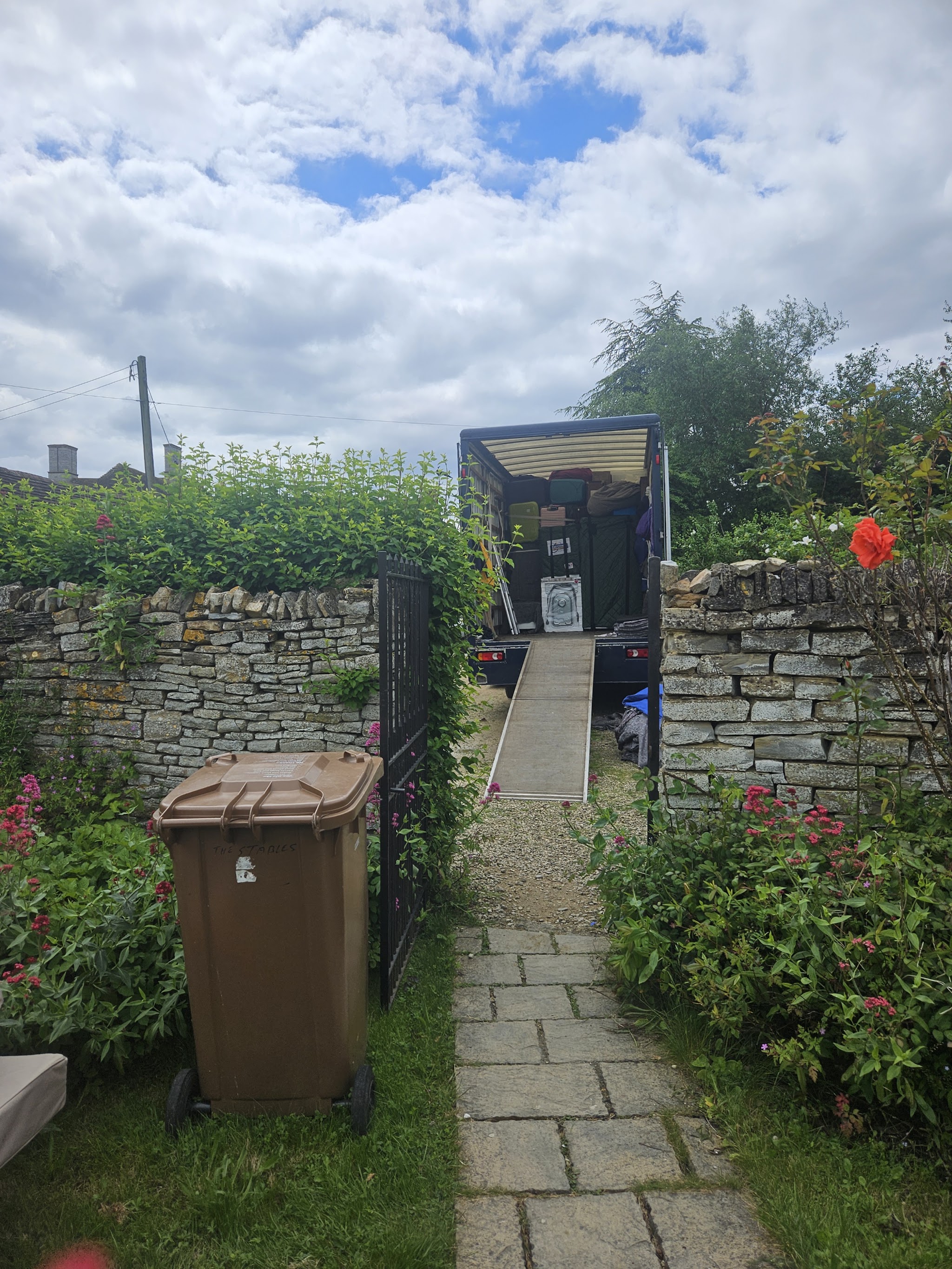 A VVP lorry with its tail-lift ramp down at the end of a garden path between stone walls
