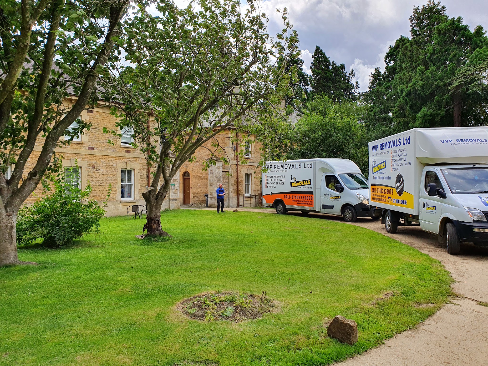 Two VVP vans on the drive of a stone building, beside a lawn and trees