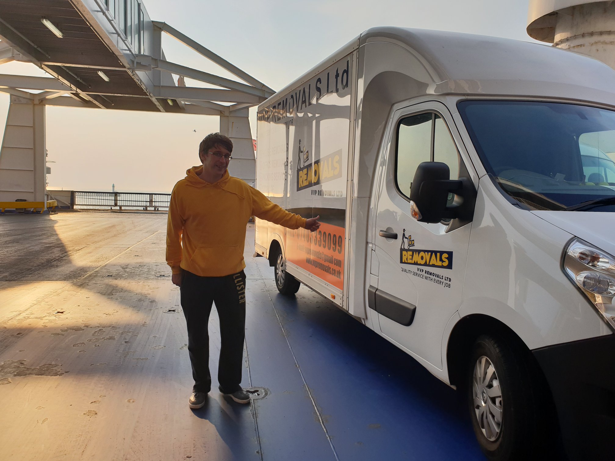 A member of the VVP team beside a VVP Removals van on the car deck of a ferry